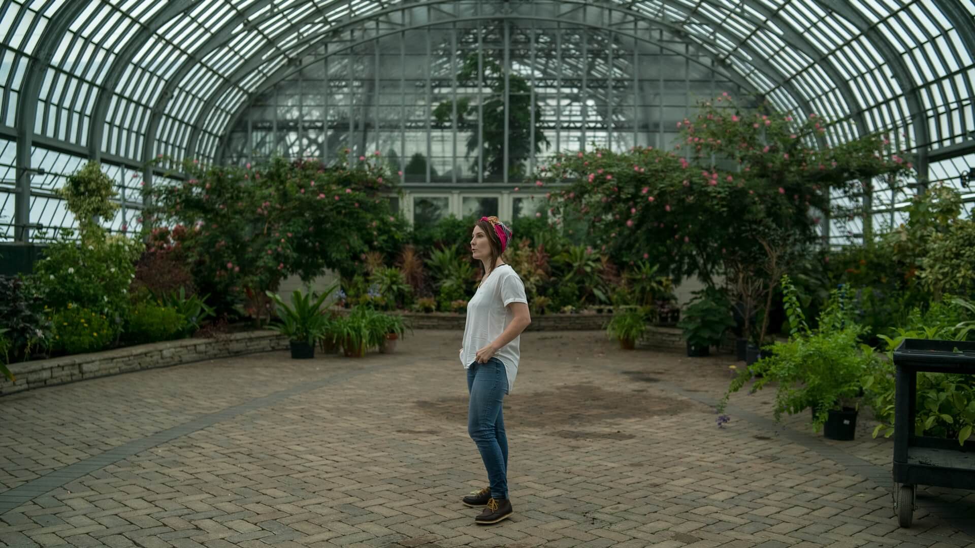 Femme dans une serre fleurie, services Épaviste et ferrailleur à Narbonne, atmosphère paisible,