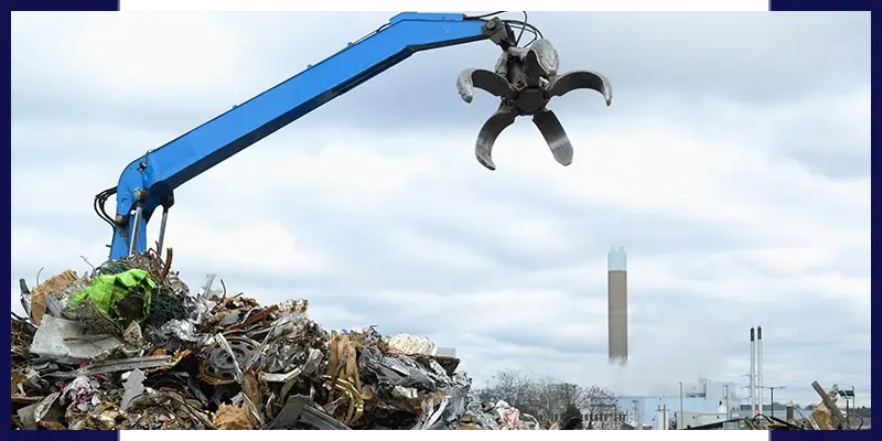 Épaviste et ferrailleur à Narbonne utilisant une pelle mécanique pour le recyclage industriel de déchets,